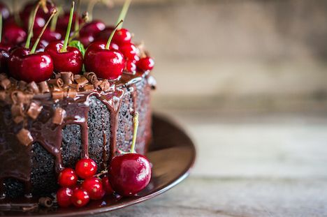 Chocolate cake with cherries on wooden background