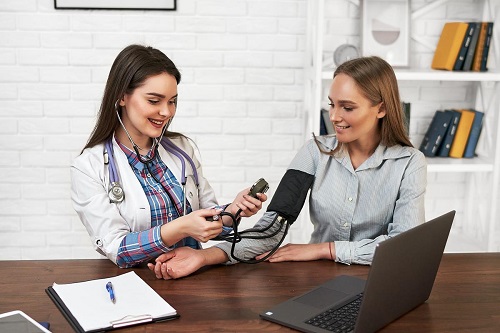 Beautiful woman at a family doctor measures blood pressure with a tonometer.