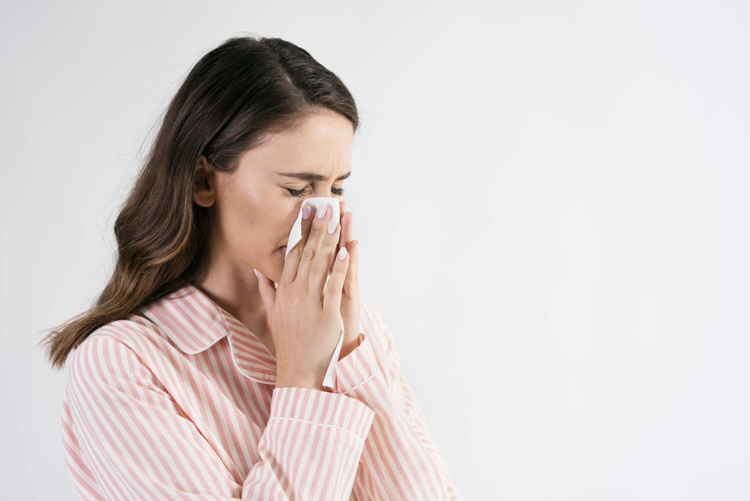 Young woman blowing her nose in studio shot